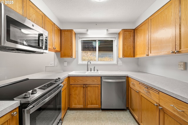 kitchen featuring appliances with stainless steel finishes, brown cabinetry, light countertops, and a sink