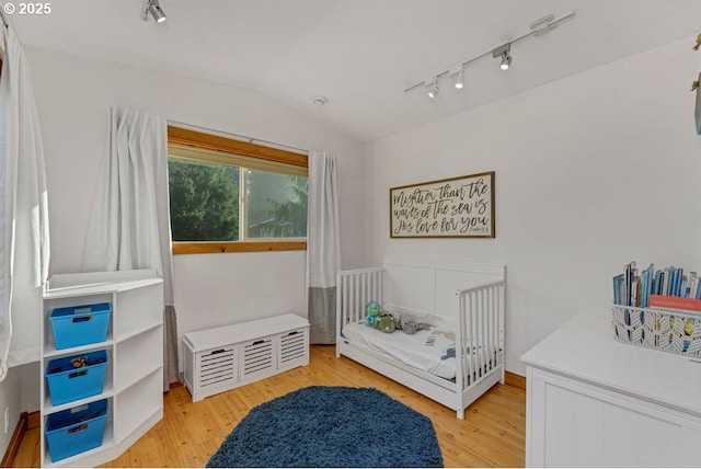 bedroom featuring lofted ceiling, track lighting, and light hardwood / wood-style floors