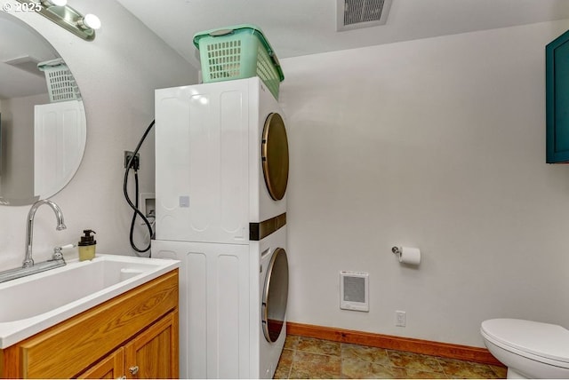 washroom with stacked washer and dryer and sink