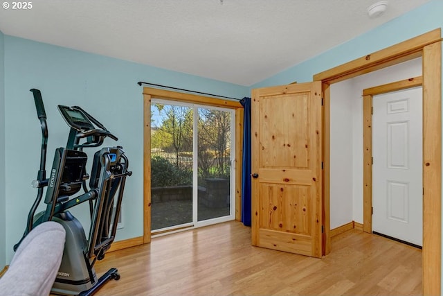 exercise area with a textured ceiling and light wood-type flooring