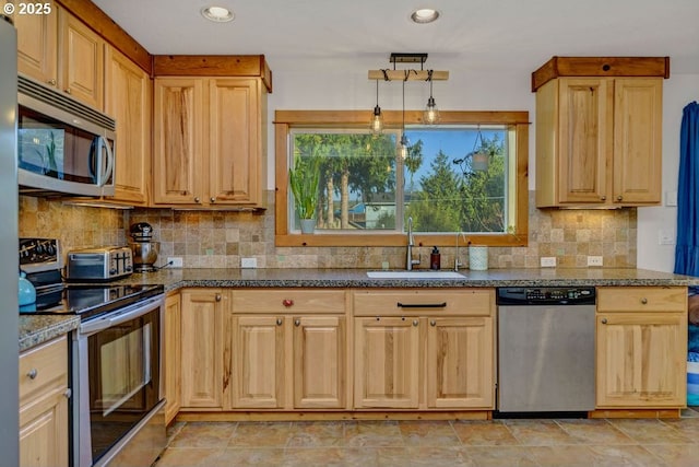 kitchen featuring pendant lighting, tasteful backsplash, sink, dark stone counters, and stainless steel appliances