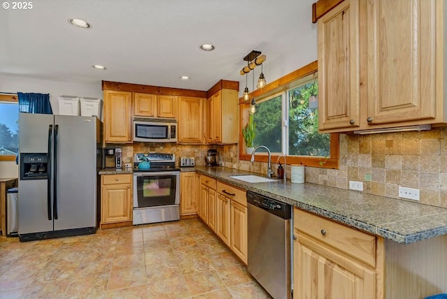 kitchen featuring stainless steel appliances, sink, backsplash, and decorative light fixtures