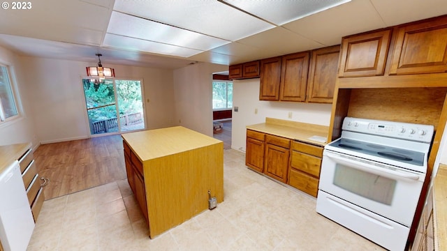 kitchen featuring a center island, white appliances, a paneled ceiling, hanging light fixtures, and a chandelier