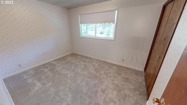 carpeted empty room featuring a textured ceiling