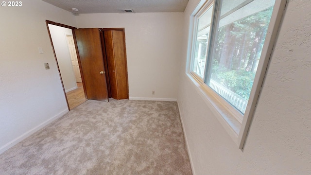 unfurnished bedroom with a textured ceiling and light carpet