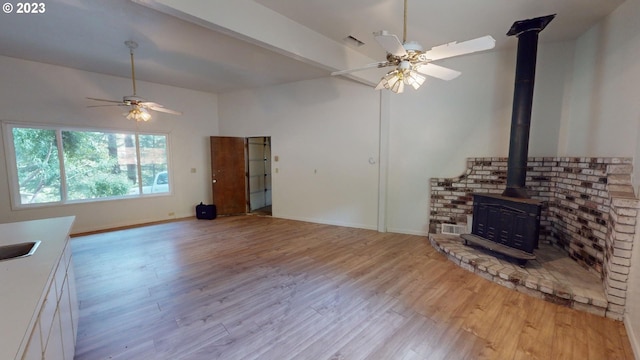 unfurnished living room with ceiling fan, light hardwood / wood-style floors, and a wood stove