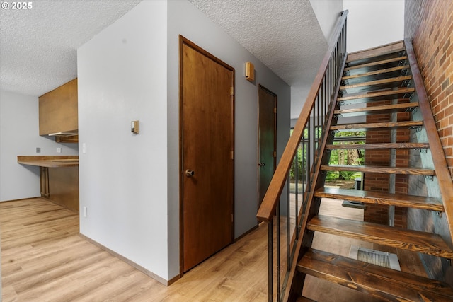 staircase with a textured ceiling and wood finished floors