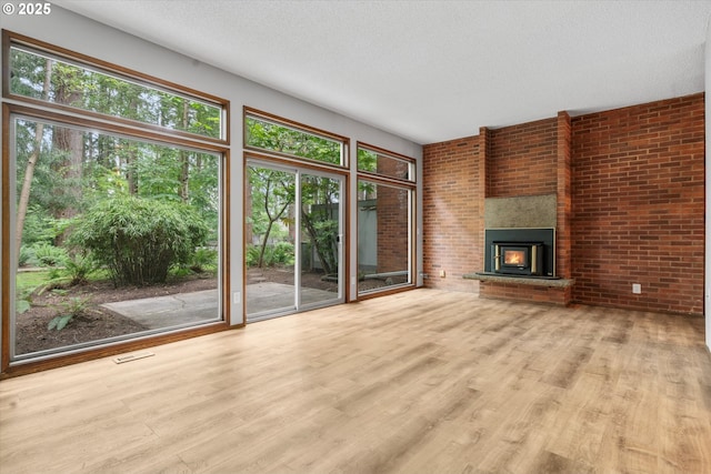 unfurnished living room featuring wood finished floors, a textured ceiling, and brick wall