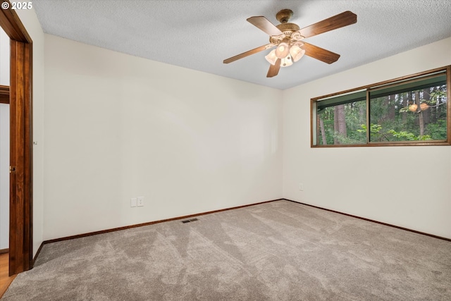 carpeted empty room with baseboards, ceiling fan, and a textured ceiling