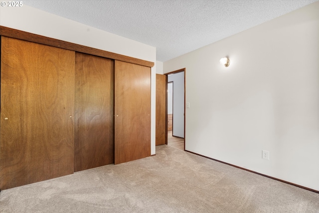 unfurnished bedroom with carpet floors, a closet, a textured ceiling, and baseboards