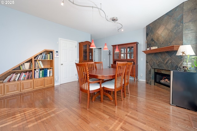 dining room with light wood finished floors, a fireplace, and baseboards