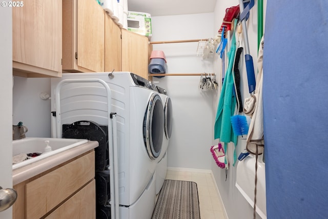 laundry area with cabinet space, light tile patterned floors, baseboards, and washing machine and clothes dryer