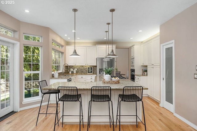 kitchen with white cabinets, light wood finished floors, tasteful backsplash, and stainless steel appliances