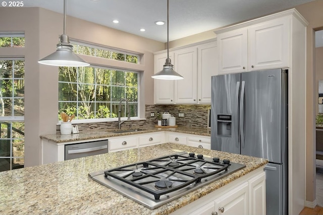 kitchen featuring appliances with stainless steel finishes, a wealth of natural light, a sink, and decorative backsplash