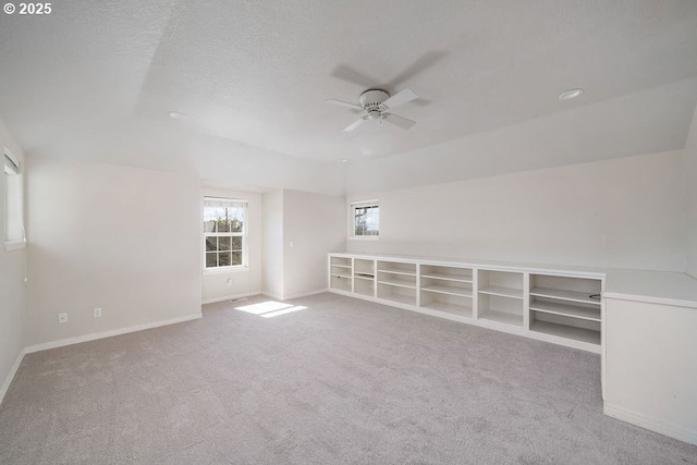 carpeted spare room with a textured ceiling, ceiling fan, and baseboards