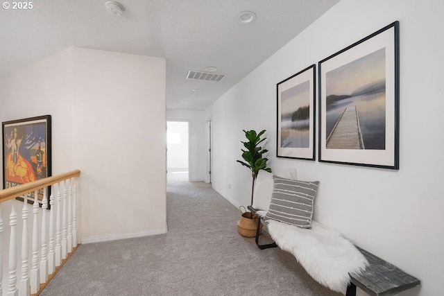 hall featuring baseboards, visible vents, and carpet flooring