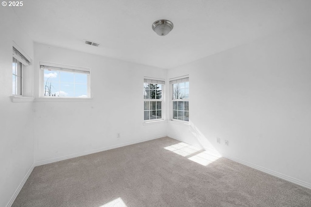 carpeted spare room featuring visible vents and baseboards