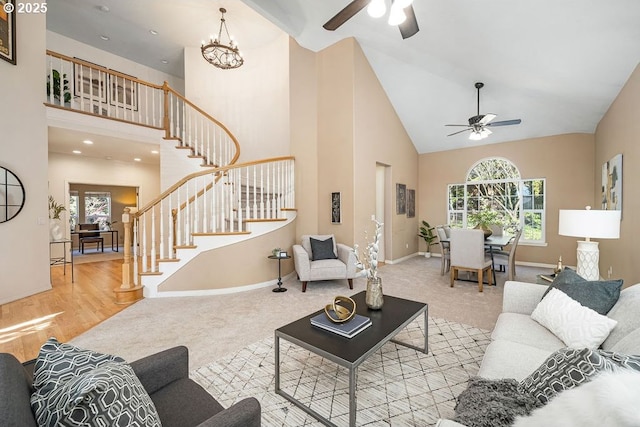 living area featuring carpet floors, stairway, high vaulted ceiling, baseboards, and ceiling fan with notable chandelier