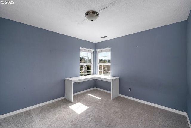 spare room with a textured ceiling, carpet, and baseboards