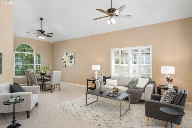 living room with baseboards, vaulted ceiling, a ceiling fan, and light colored carpet