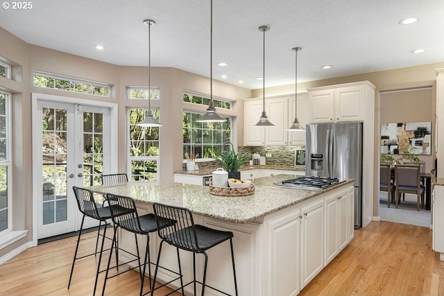 kitchen featuring light stone counters, french doors, light wood finished floors, white cabinets, and a kitchen island