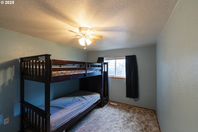 bedroom with ceiling fan, carpet floors, and a textured ceiling