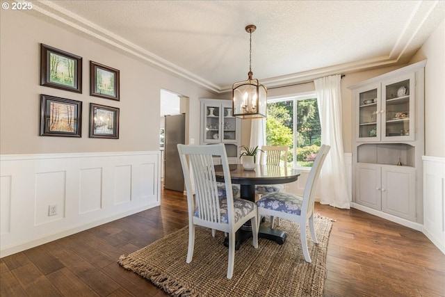 14940 SW Michael Ct, Sherwood, OR 97140 - dining area featuring a chandelier, a textured ceiling, dark wood finished floors, wainscoting, and crown molding