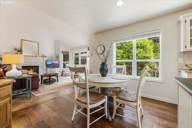 14940 SW Michael Ct, Sherwood, OR 97140 - dining area with dark wood-type flooring, a glass covered fireplace, baseboards, and vaulted ceiling