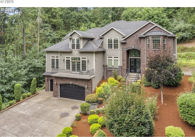 view of front of house with french doors, brick siding, roof with shingles, a garage, and driveway