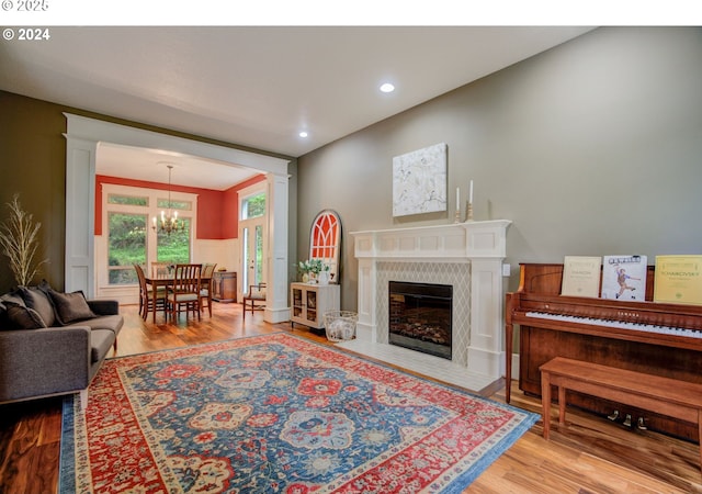 living room featuring recessed lighting, a fireplace with flush hearth, wood finished floors, wainscoting, and an inviting chandelier