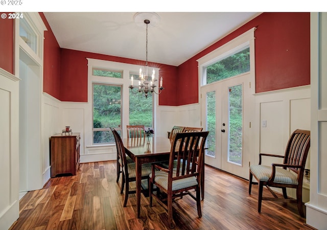 dining room featuring french doors, dark wood-type flooring, wainscoting, and a decorative wall