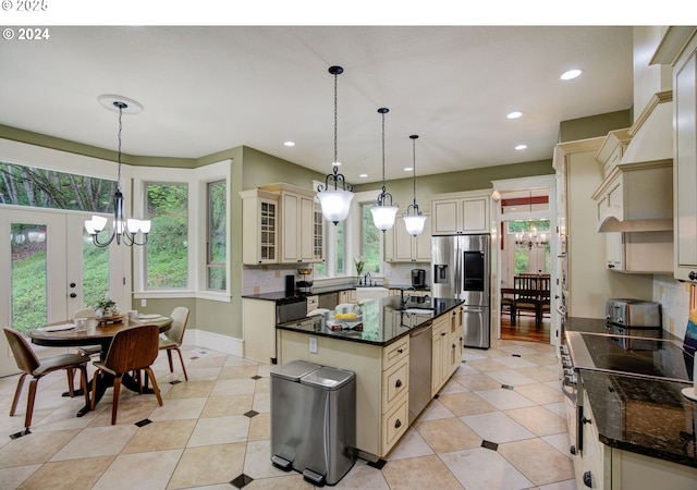 kitchen featuring appliances with stainless steel finishes, cream cabinetry, custom exhaust hood, and an inviting chandelier