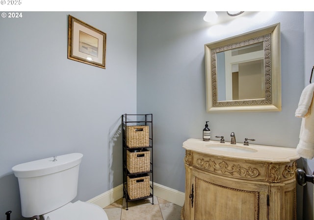 half bathroom with tile patterned flooring, baseboards, vanity, and toilet