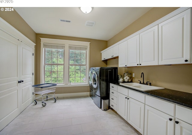 laundry area with washing machine and clothes dryer, cabinet space, visible vents, a sink, and baseboards