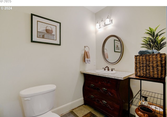 half bathroom with toilet, baseboards, and vanity