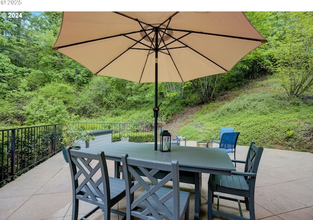 view of patio with outdoor dining area and a view of trees