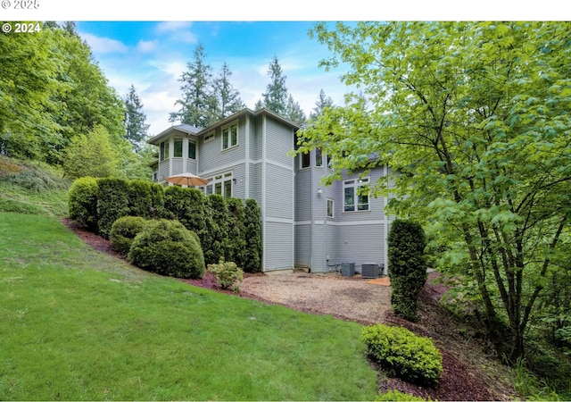 view of side of home with a yard and central AC unit