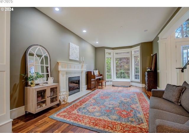 living room featuring baseboards, wood finished floors, a fireplace with flush hearth, and recessed lighting