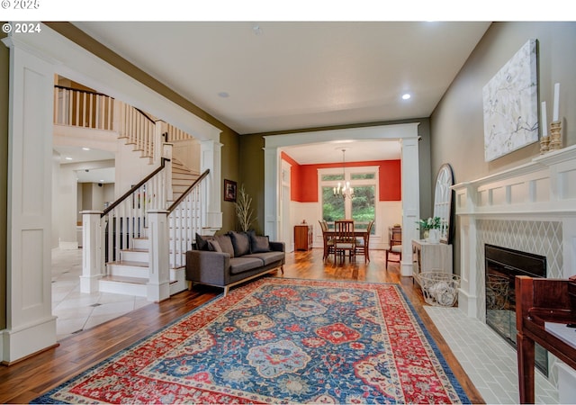 living room with a decorative wall, a wainscoted wall, wood finished floors, a high end fireplace, and stairway