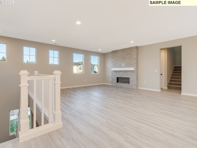 unfurnished living room featuring light wood finished floors, recessed lighting, a fireplace, and baseboards