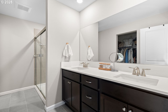 bathroom with a spacious closet, a sink, visible vents, and a shower stall