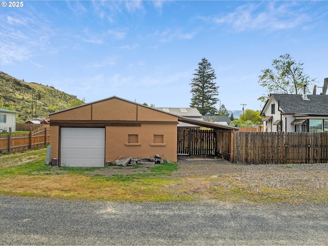 view of property exterior with fence, an outbuilding, a garage, and a mountain view