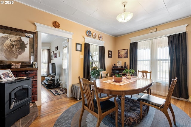 dining space featuring light wood-type flooring, a wood stove, and ornamental molding