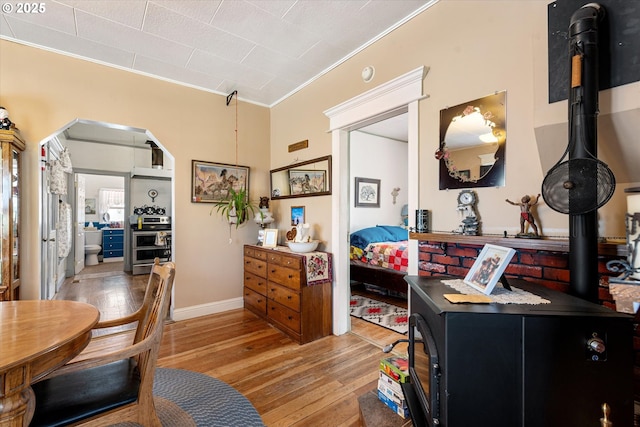 bedroom with light wood-style flooring, crown molding, and arched walkways