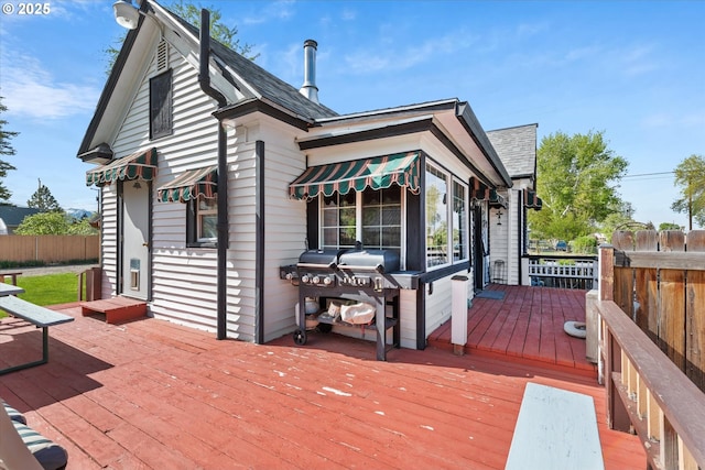 rear view of property with a wooden deck, fence, and roof with shingles