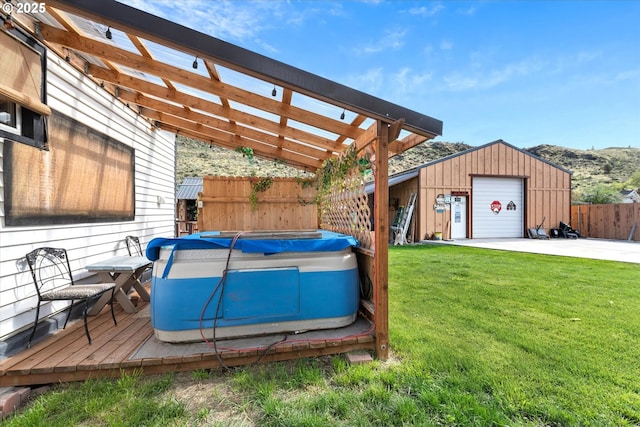 deck with a hot tub, a detached garage, an outdoor structure, concrete driveway, and a pergola