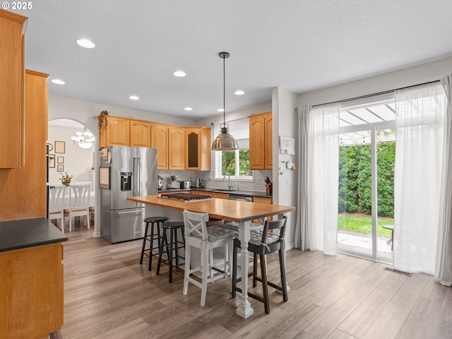 17717 NE 26th St, Vancouver, WA 98684 - kitchen featuring appliances with stainless steel finishes, light wood-style floors, a kitchen breakfast bar, decorative backsplash, and a kitchen island
