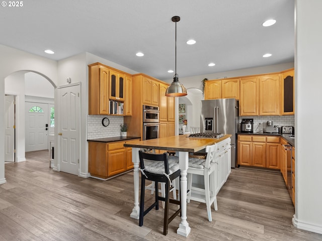 17717 NE 26th St, Vancouver, WA 98684 - kitchen with arched walkways, stainless steel appliances, backsplash, glass insert cabinets, and recessed lighting