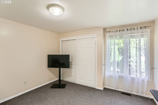 17180 NW Joscelyn St, Beaverton, OR 97006 - unfurnished bedroom with dark colored carpet, a textured ceiling, baseboards, and a closet