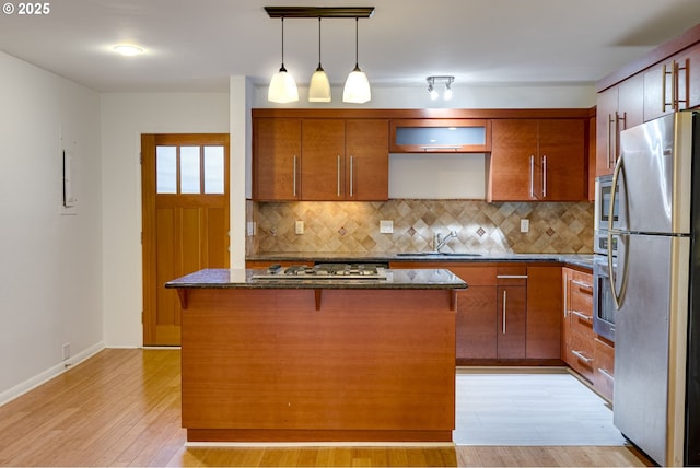 kitchen featuring sink, decorative light fixtures, a center island, appliances with stainless steel finishes, and dark stone counters